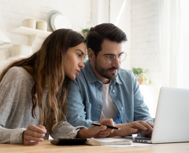 Young couple viewing a laptop together researching loans