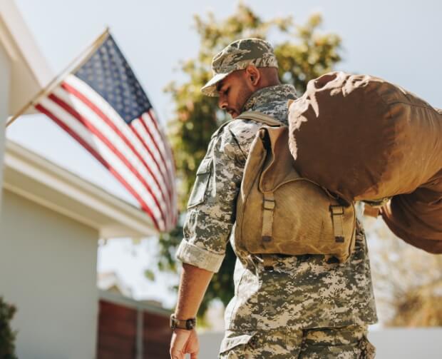 Veteran with gunny sack coming home to an American Flag