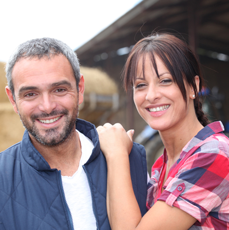 Couple in front of barn with hay 