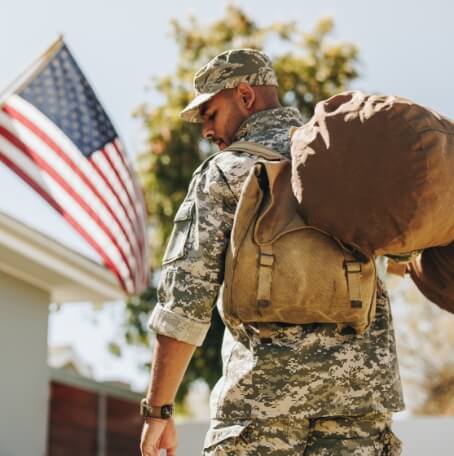 Veteran with gunny sack coming home to an American Flag