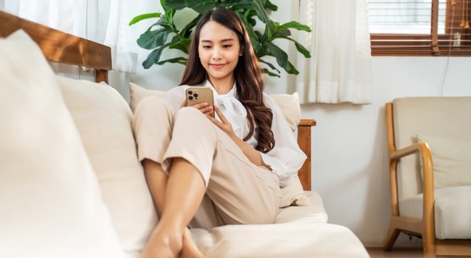 Young lady looking at smart phone smiling.